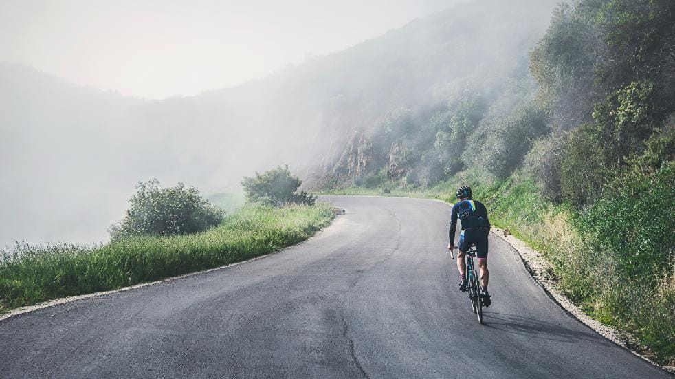 older man cycling on road